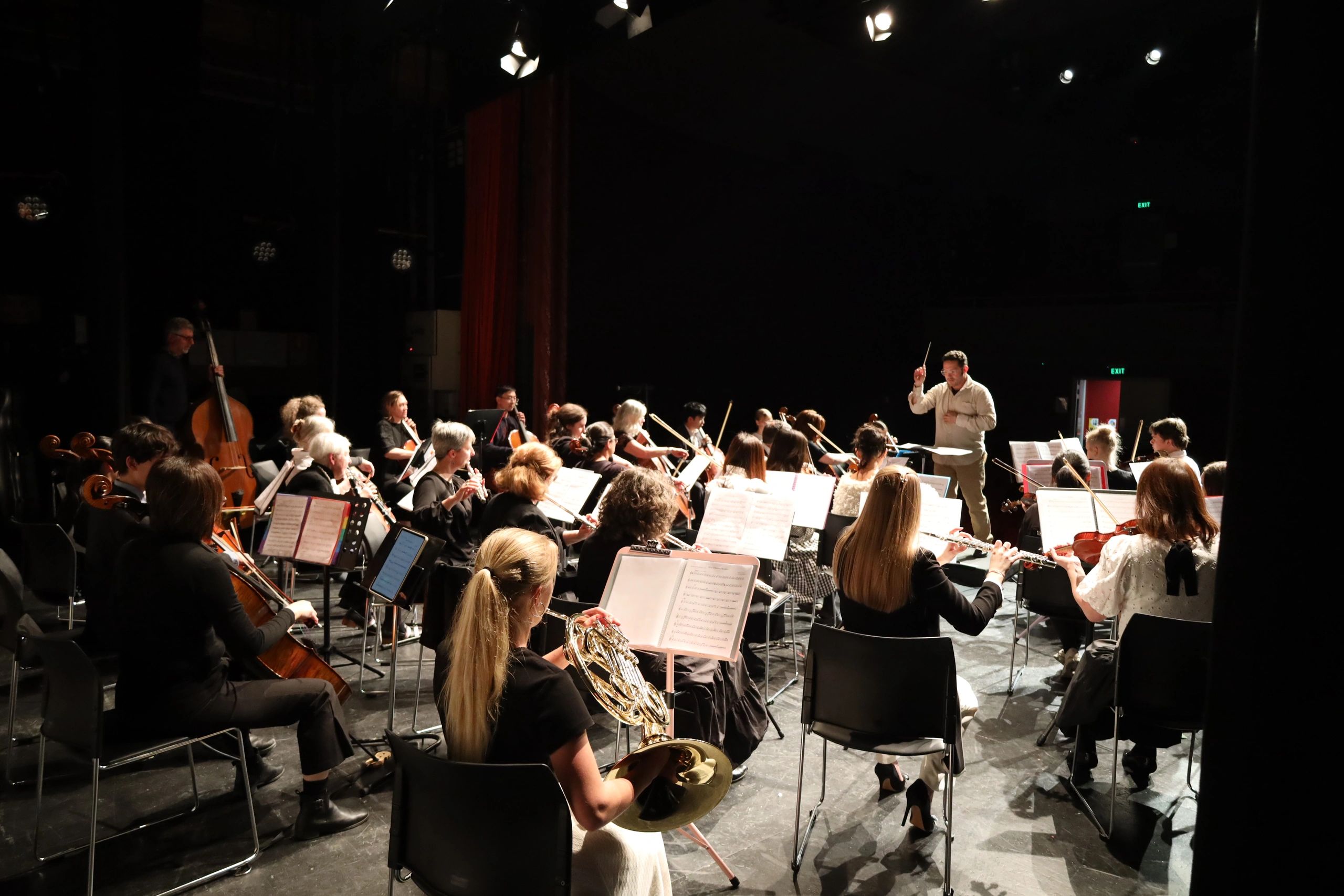 Orchestra performing on stage with a conductor leading.