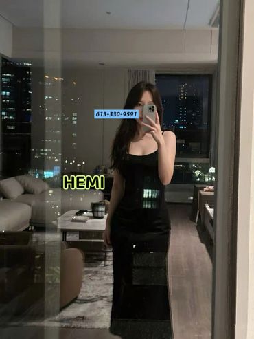 Woman in a black dress taking a mirror selfie in a modern apartment at night.