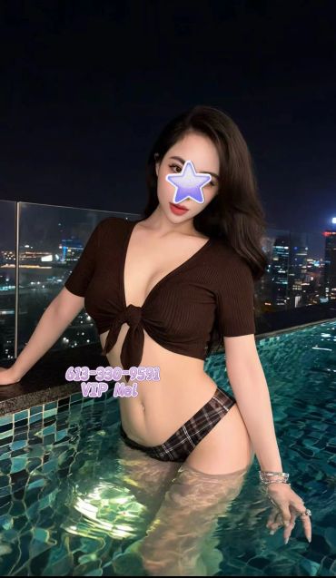 Woman posing in a pool at night with city lights in the background.