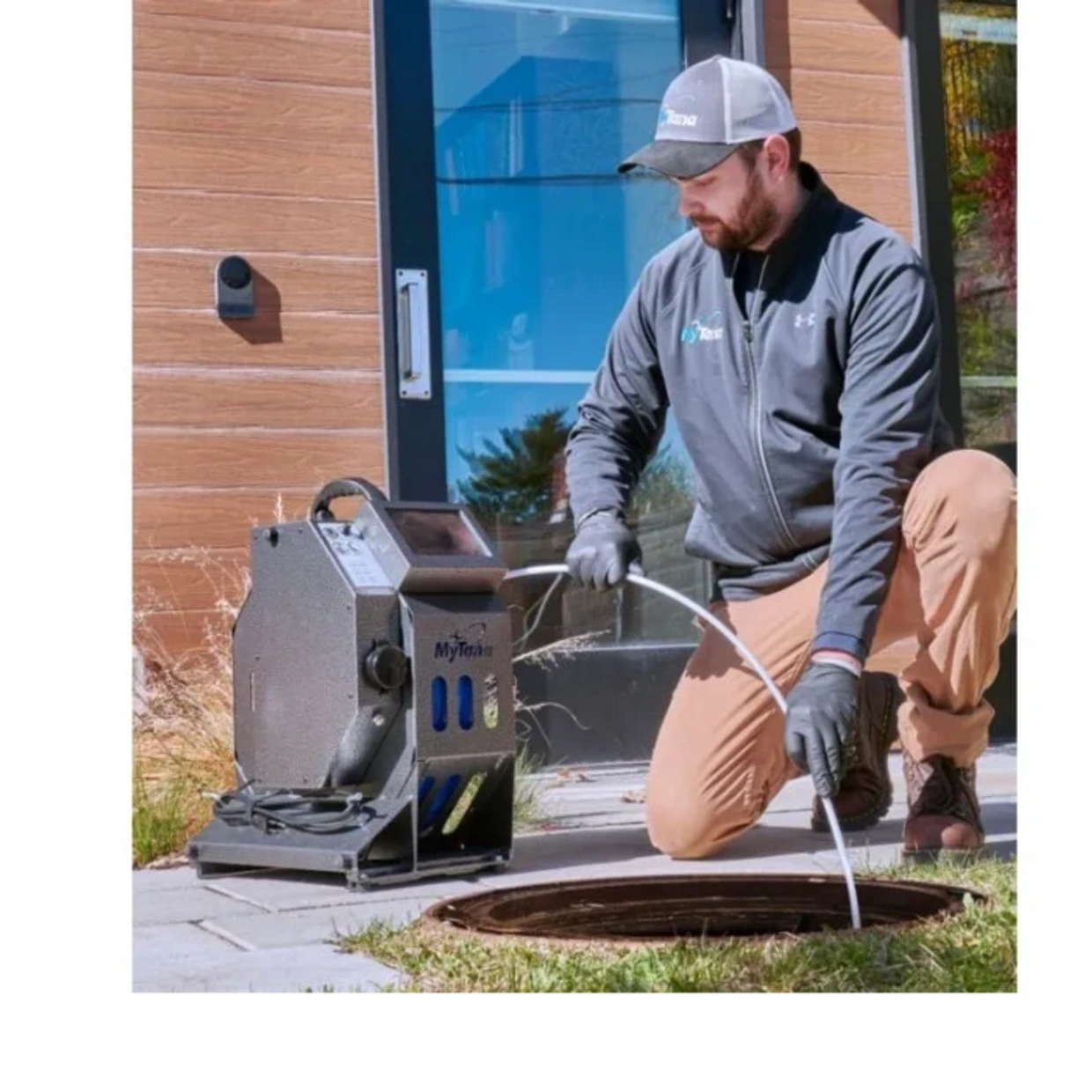 Technician inspecting a sewer line with a MyTana inspection camera outdoors.