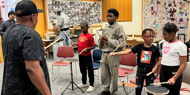 Group of kids learning drums from an instructor.