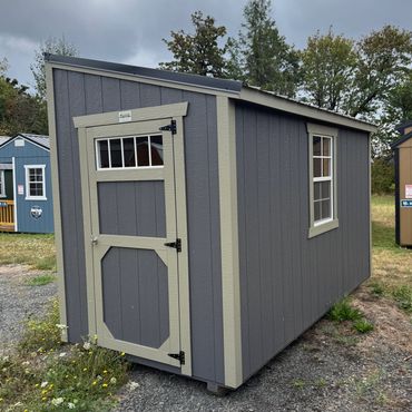 Small gray garden shed with a window and a door.