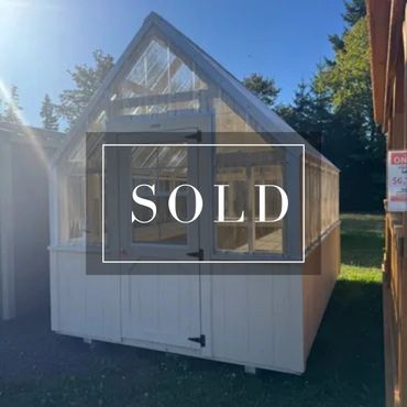 A sold white greenhouse with a clear roof on a sunny day.