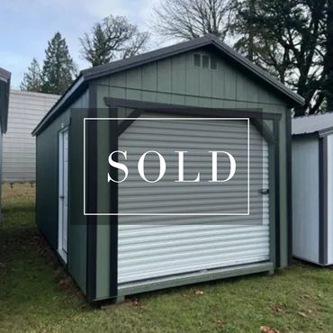A green storage shed with a white roll-up door labeled 'SOLD'.