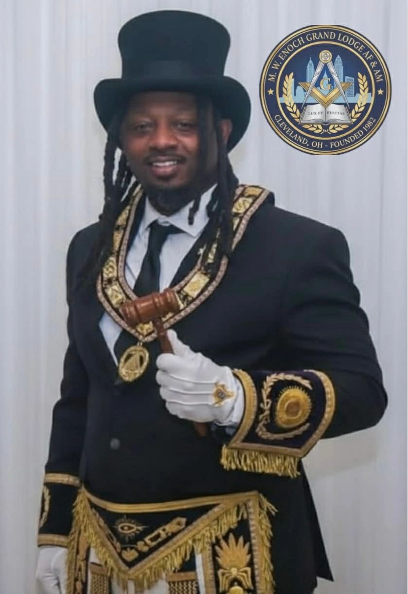 Man in ornate Masonic regalia holding a gavel, with a top hat and white gloves.