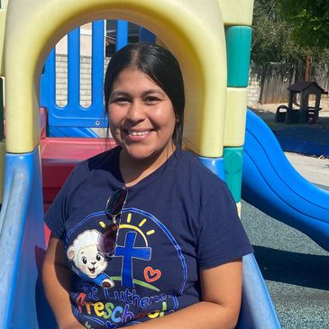 Smiling woman sitting on a playground slide.