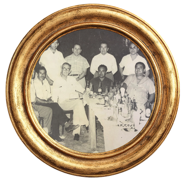 Foto antigua en blanco y negro con ocho hombres en una mesa.