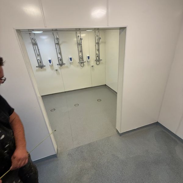 A man measures a newly installed shower area with multiple showerheads.