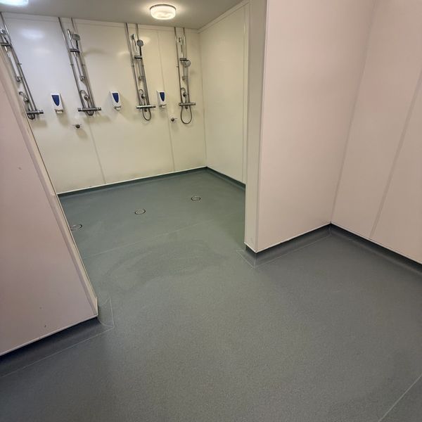 A clean, modern communal shower area with multiple showerheads and soap dispensers.