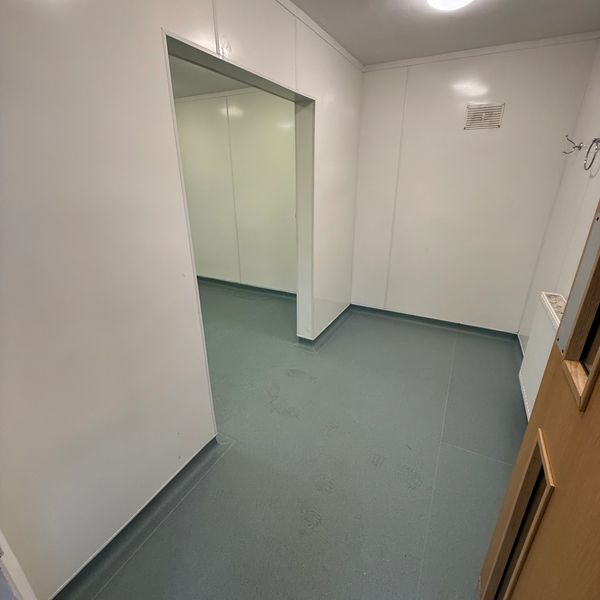 Empty room with white walls and green flooring under soft lighting.