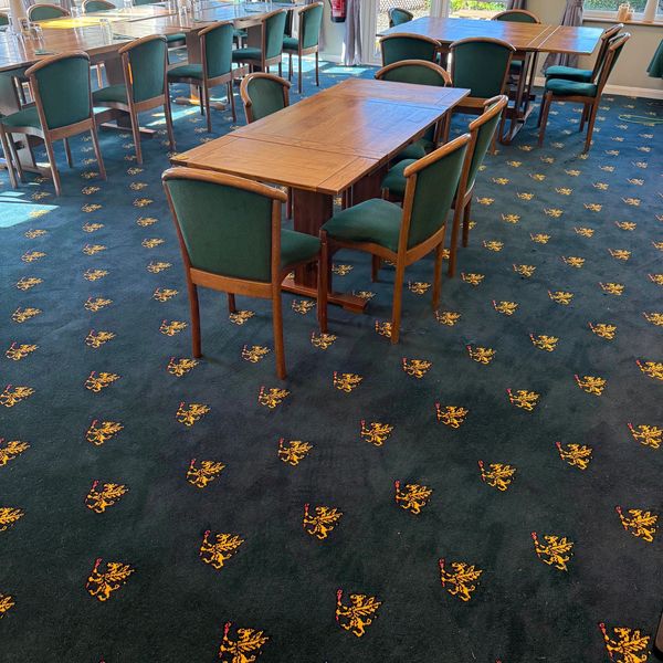 Wooden tables and green chairs in a carpeted room.