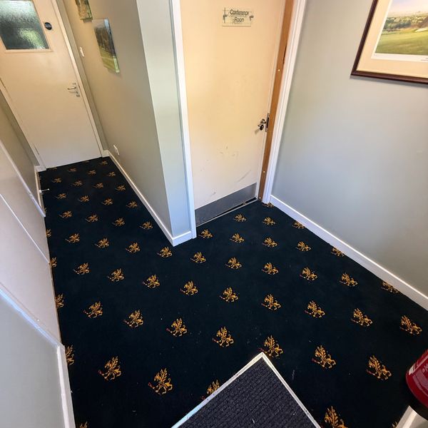 Hallway with patterned carpet leading to a conference room.