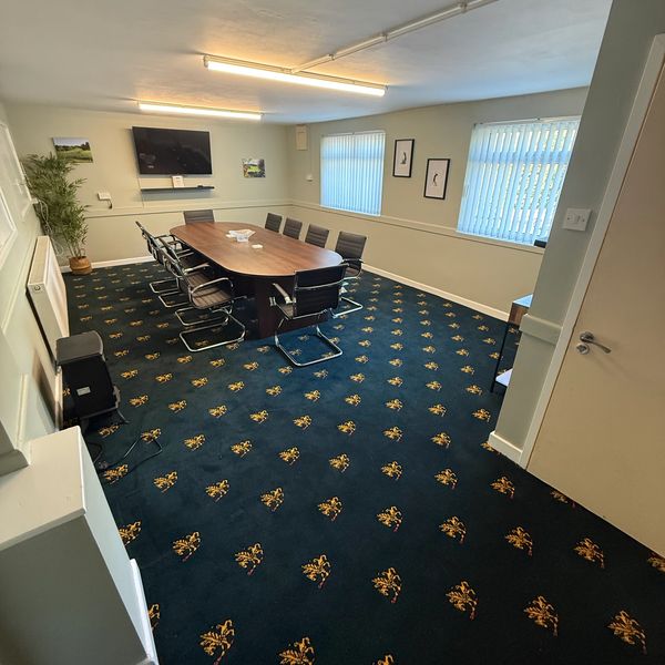 A modern conference room with a wooden table and chairs.
