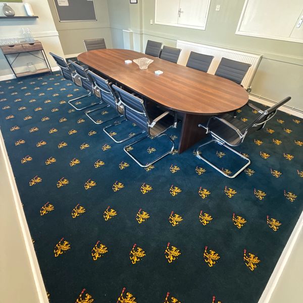 Conference room with oval wooden table and black chairs.