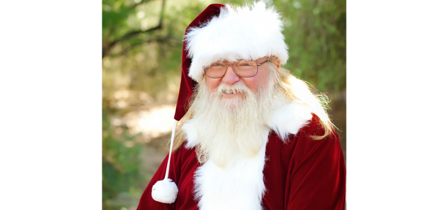 A child in a Santa hat decorates a Christmas tree with ornaments.