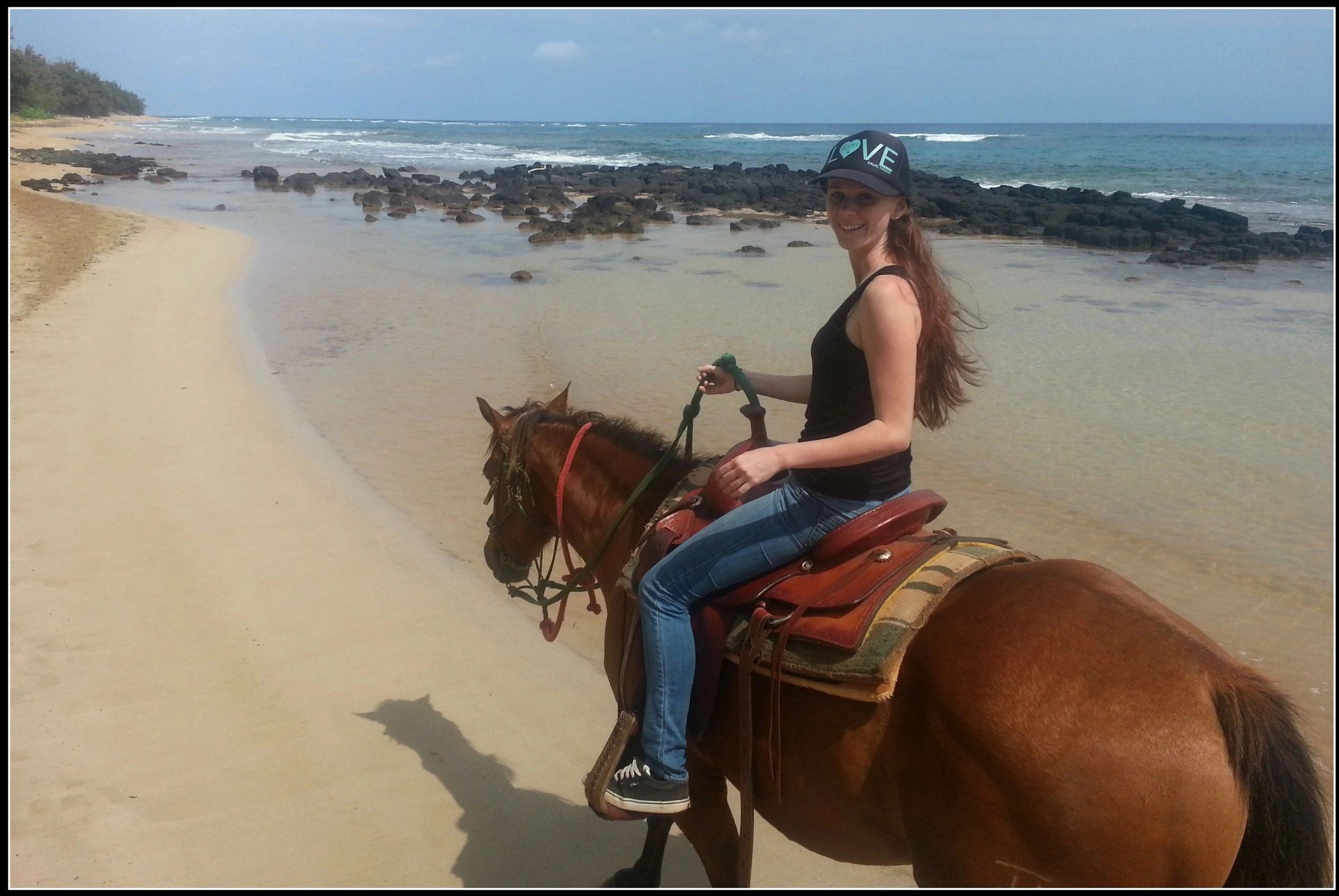 women on horseback walking along beach