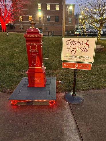 Red mailbox and sign for mailing letters to Santa at night.