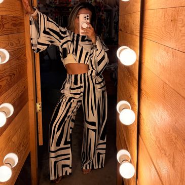 Person taking mirror selfie wearing black and white striped outfit.