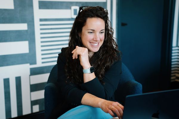 Smiling woman working on a laptop in a modern office setting.