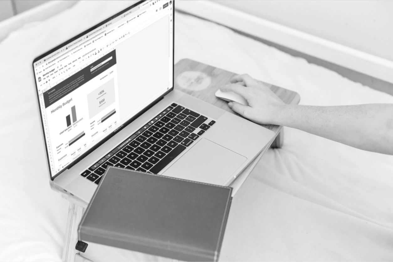 Feminine hand on mouse with notebook and pen, a coffee cup, and a keyboard.