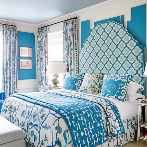 Bright blue and white bedroom with patterned bedding and an elegant headboard.