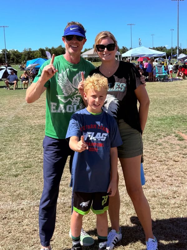 A happy family posing with number one signs at a sports field.