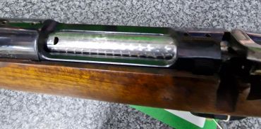Close-up of a rifle's bolt action and wooden stock.