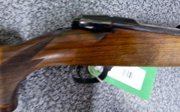 Close-up of a wooden rifle stock with a tag.