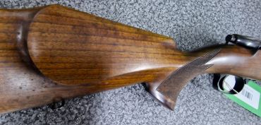 Wooden rifle stock on a gray surface.