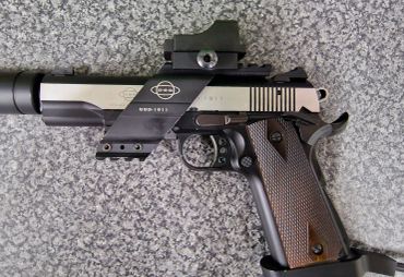 Tactical handgun with mounted sight on granite surface.
