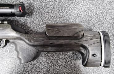 Close-up of a rifle stock with an adjustable cheek rest and scope mount.