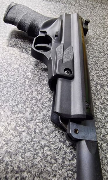 Close-up of a black handgun on a textured surface.