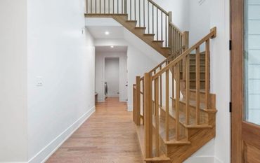 Modern hallway with wooden stairs and light wood flooring.