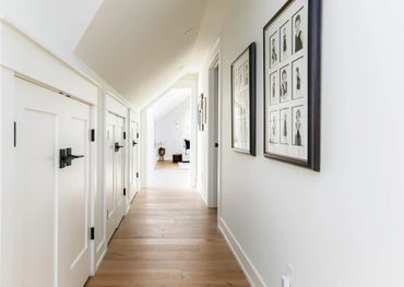 Bright hallway with wooden flooring and framed photos on the wall.