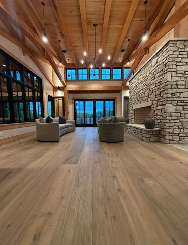 Spacious living room with wooden ceiling, stone fireplace, and modern furniture.
