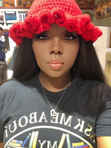 Woman with long hair wearing a red knitted hat and a black graphic tee.