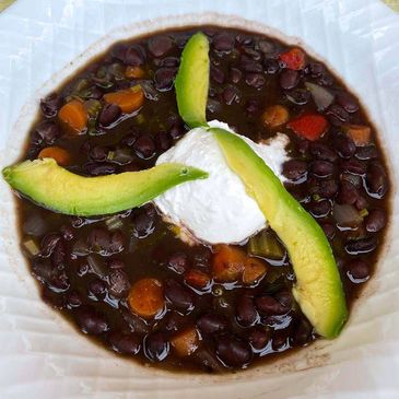 Black bean soup, topped with sour cream and three avocado slices.