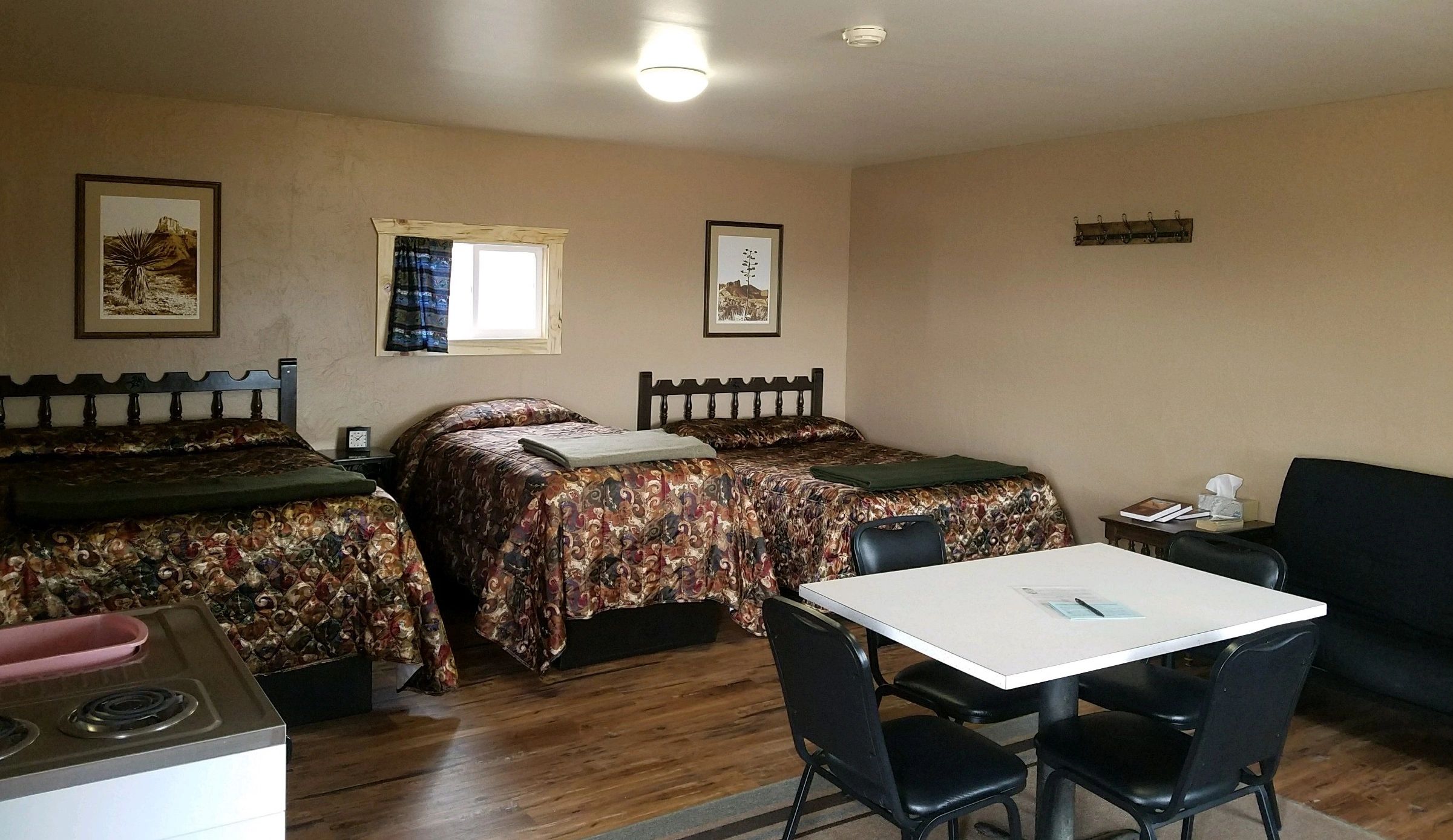 A wide view of a hotel room with two beds, a sofa, a table, and a window.