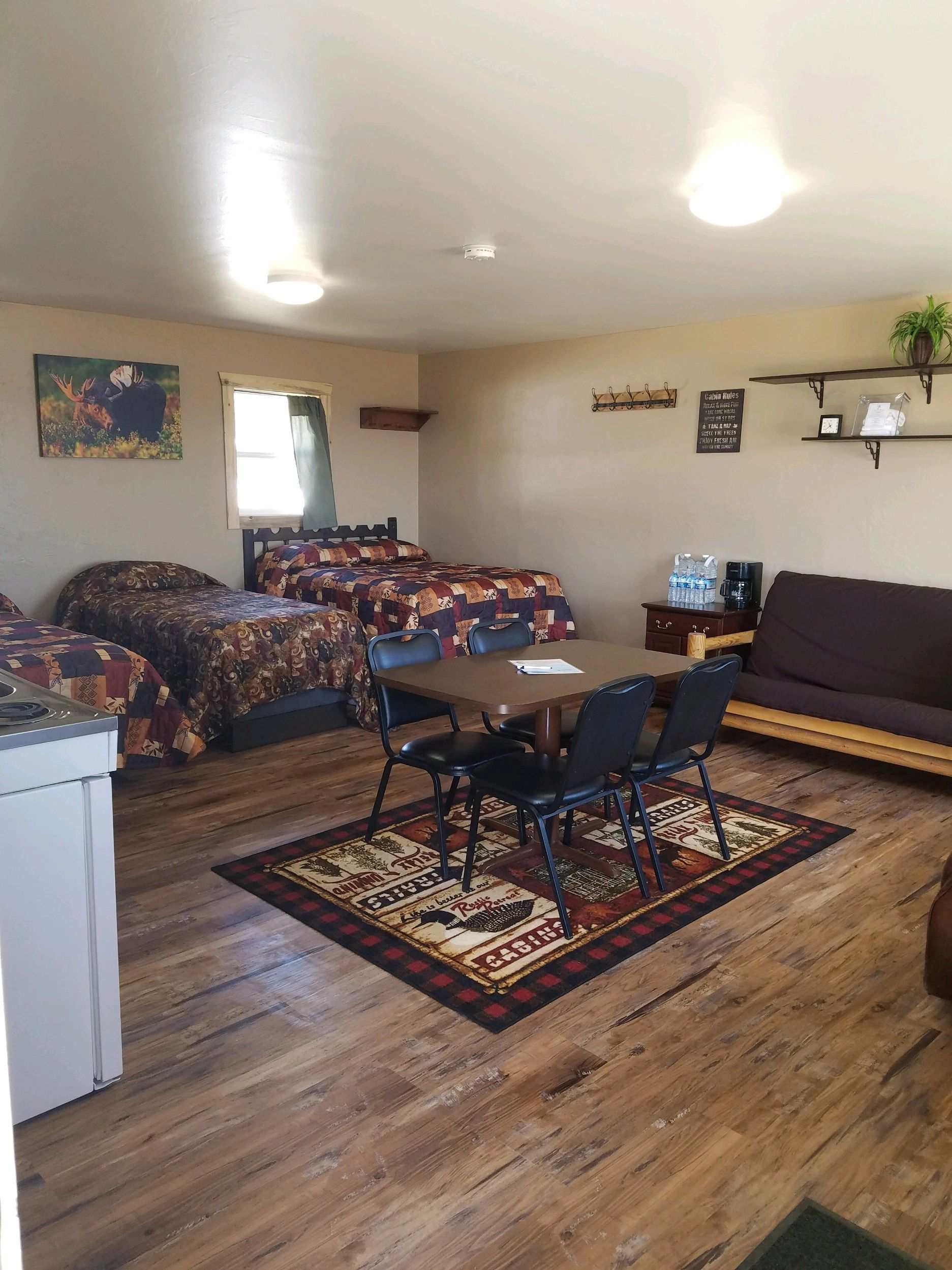 A wide-angle view of a hotel room with two beds, a table, and a futon.