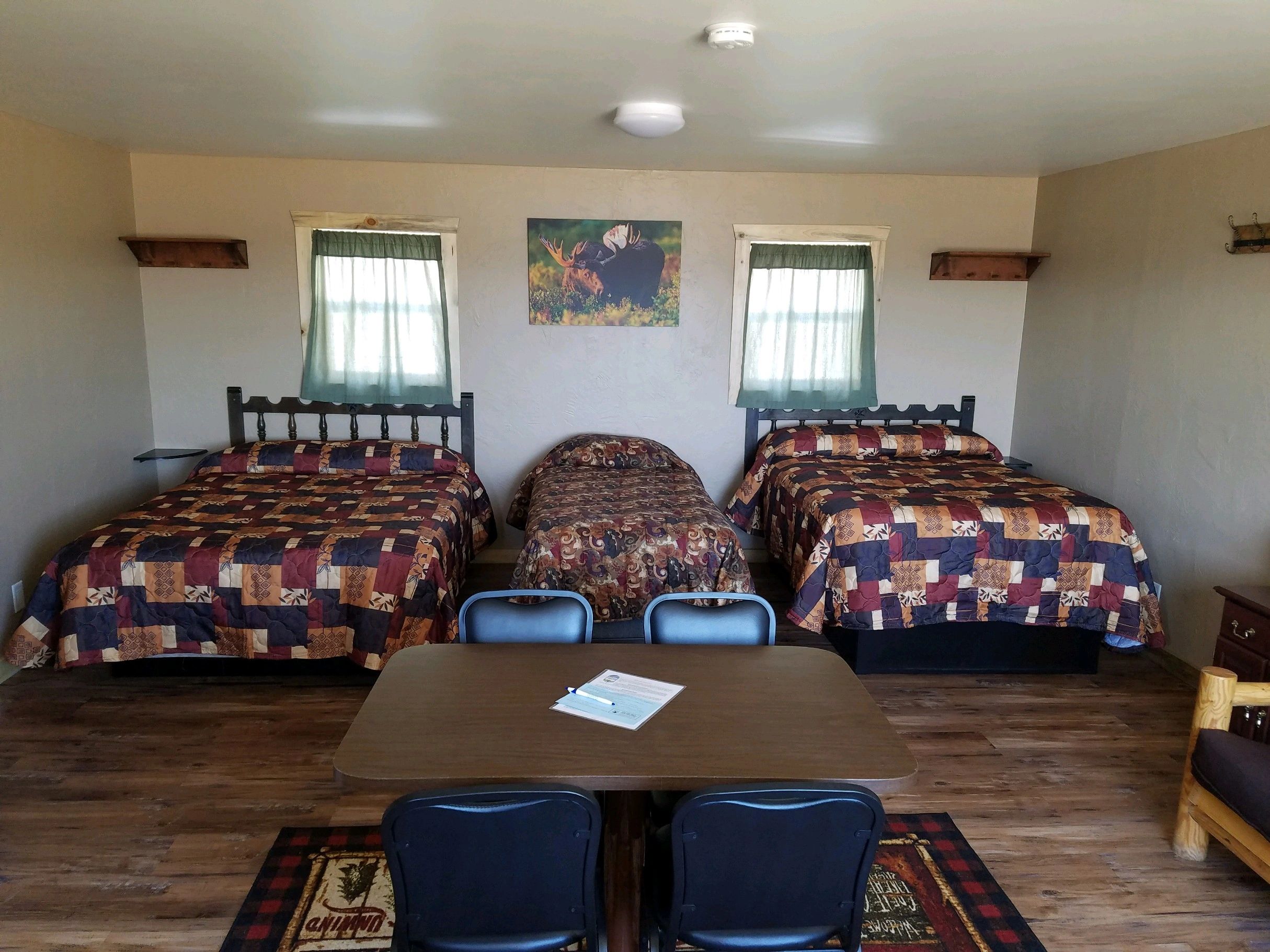 A room with three beds, a desk, and chairs