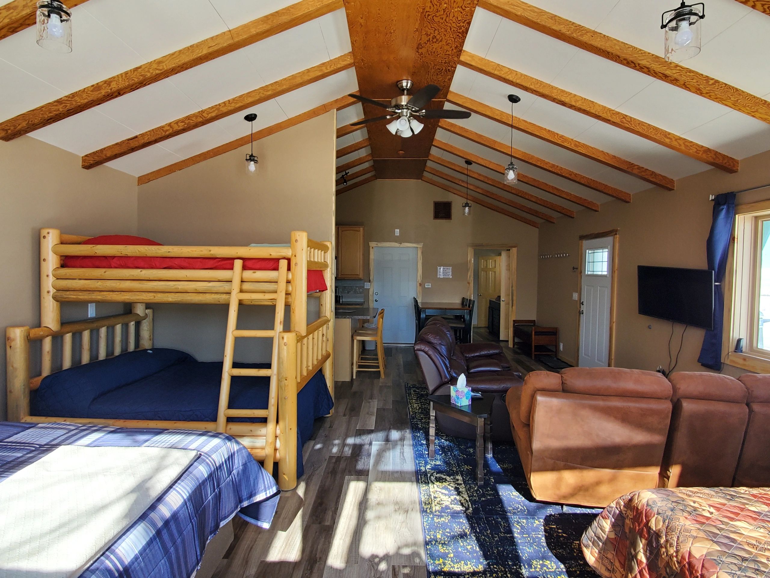 A wide view of a suite with bunk bed, sofa, TV, and kitchenette.