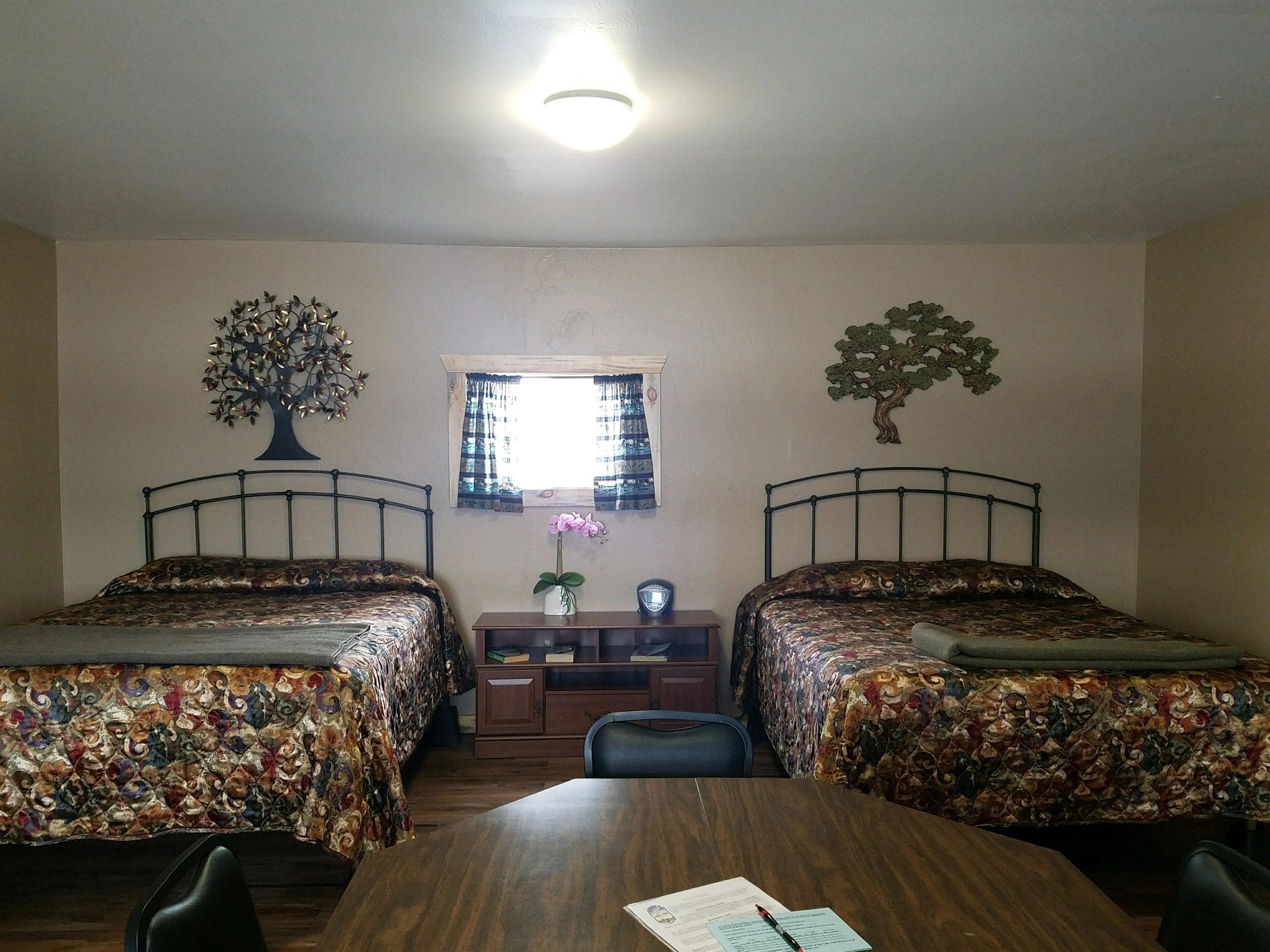 A hotel room with two beds, a desk, and a window.