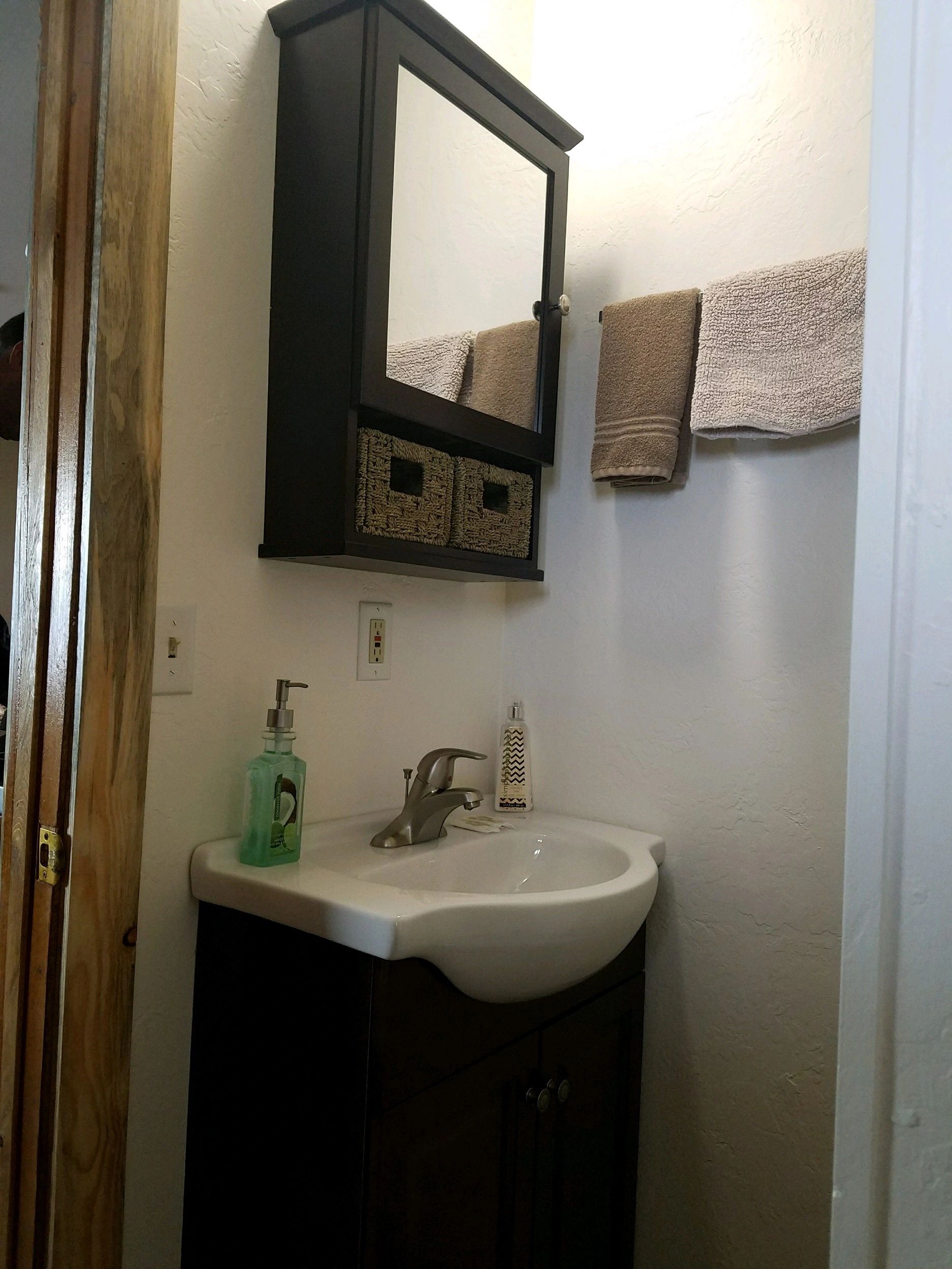 A bathroom sink with a mirror and towels