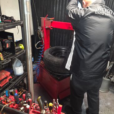 Man working on a tire with tools in a garage.