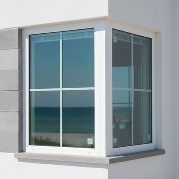 Modern white-framed corner window reflecting the ocean view.