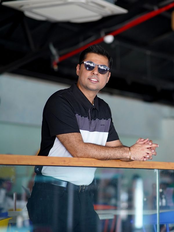 Man in sunglasses leaning on a glass railing indoors.