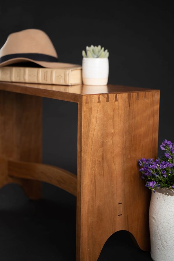 Curved cherry entryway bench with hand cut dovetails.