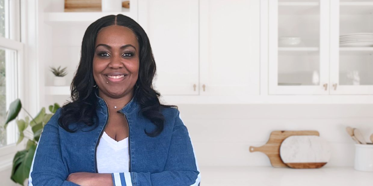 Confident woman smiling with arms crossed in a bright modern kitchen.