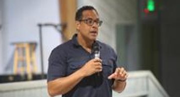 Man speaking into a microphone indoors.