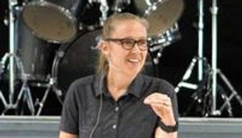 Woman smiling with drum set in background.